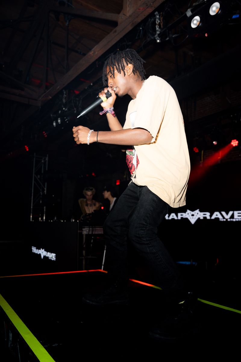 HARLEM performing in profile at Warehouse 1720 with the Trap Rave screen behind him